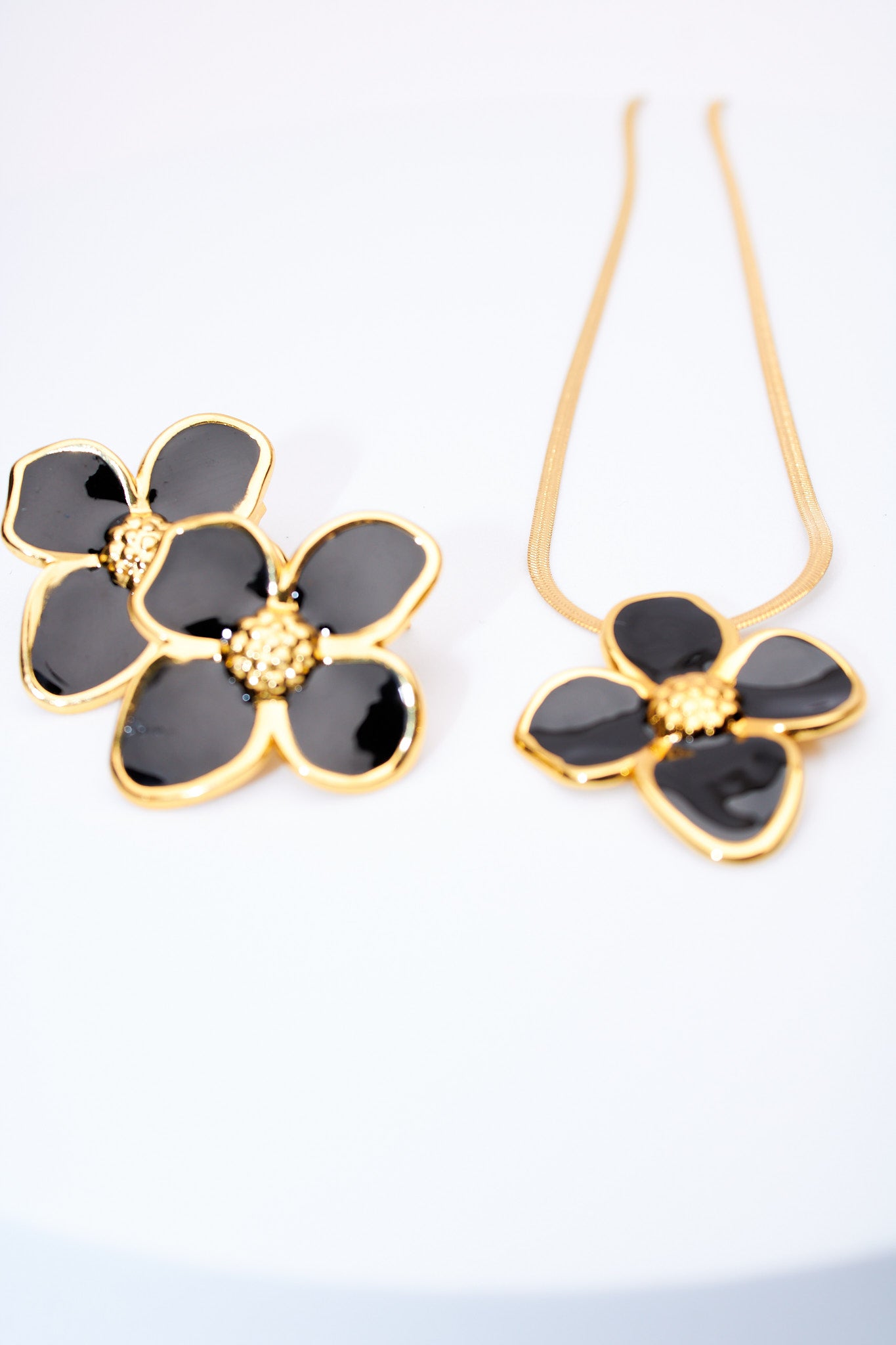 Set flor esmaltada negra — collar serpiente + broches flor, baño dorado
