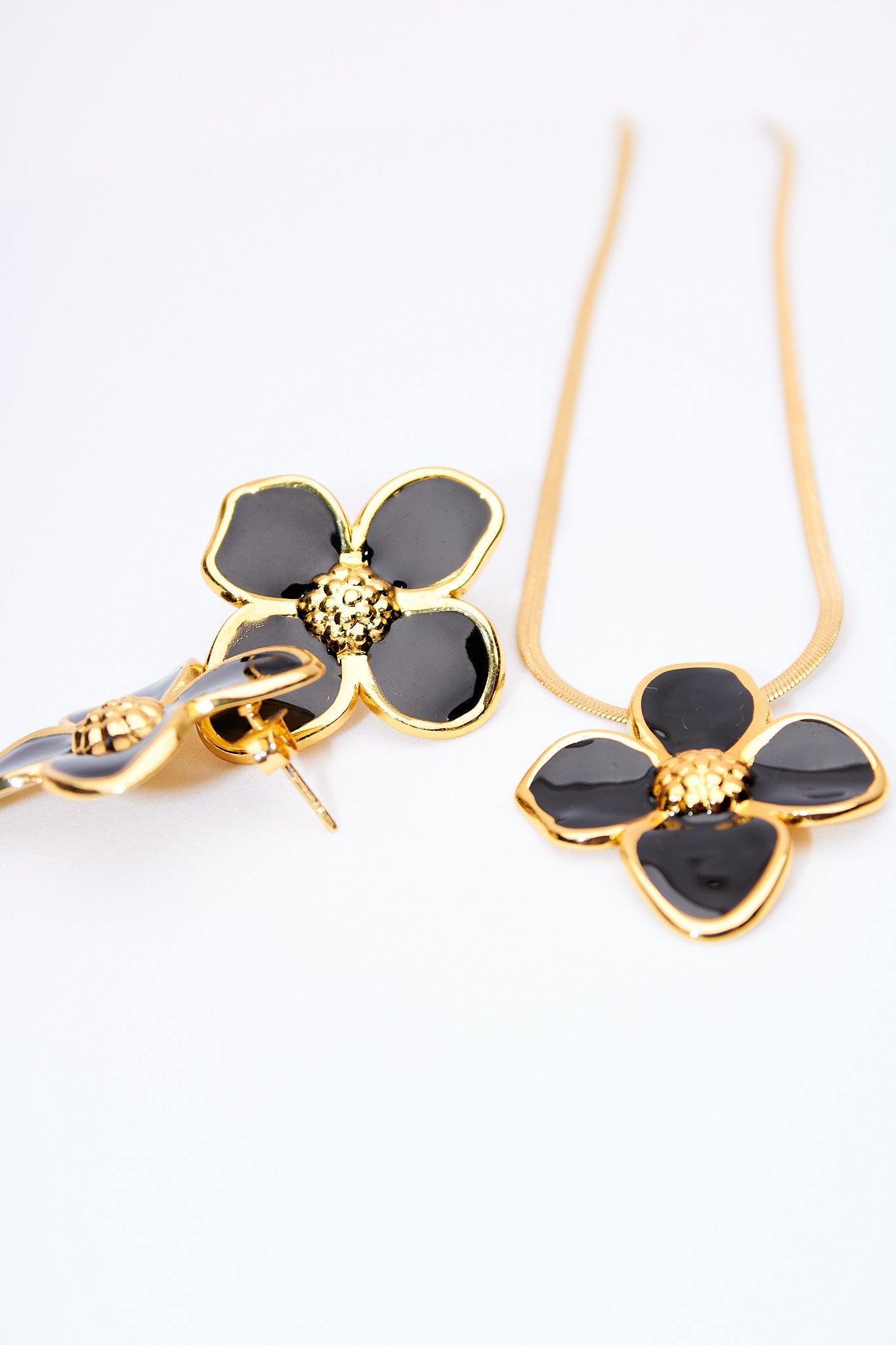 Set flor esmaltada negra — collar serpiente + broches flor, baño dorado