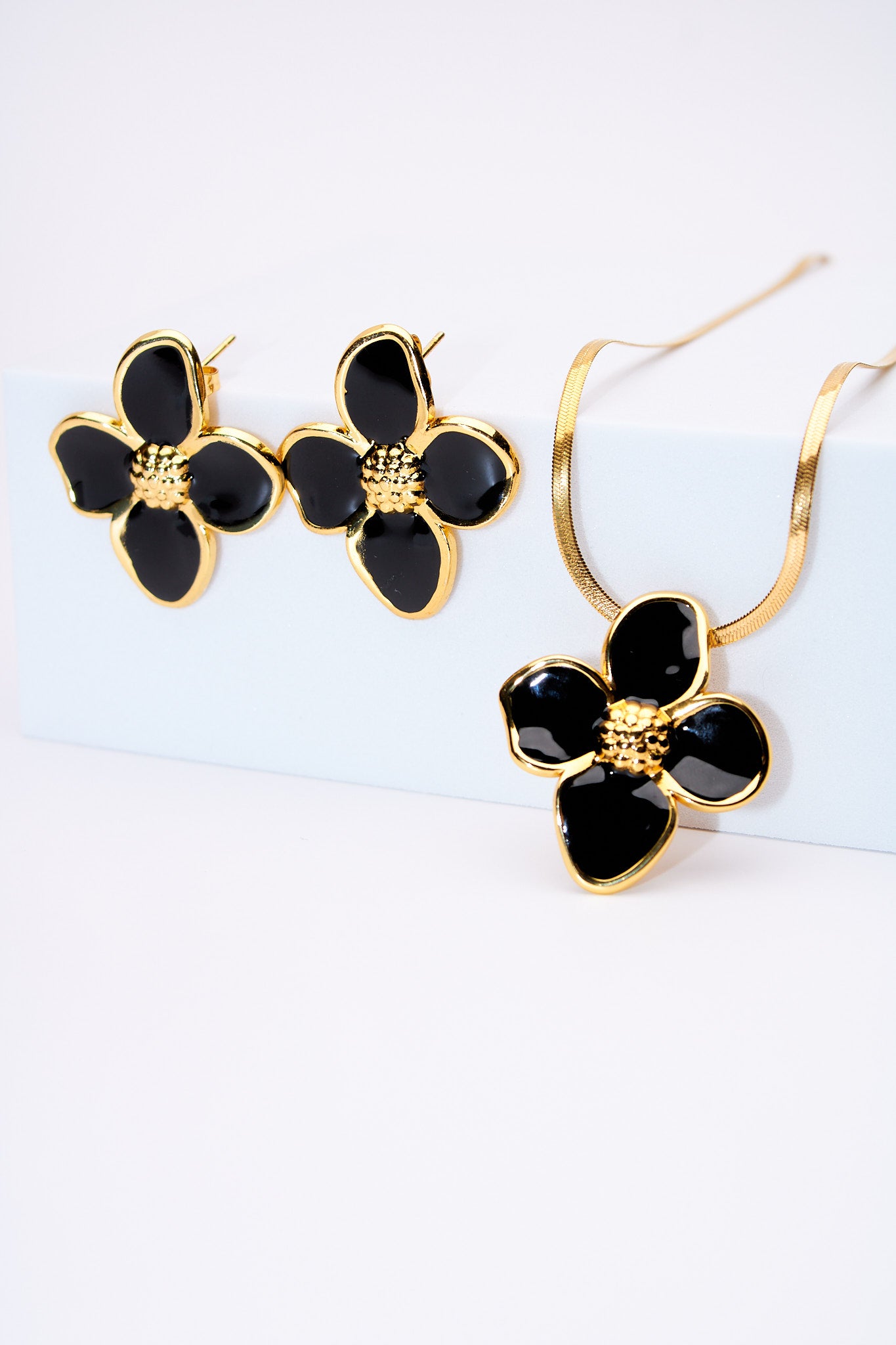 Set flor esmaltada negra — collar serpiente + broches flor, baño dorado