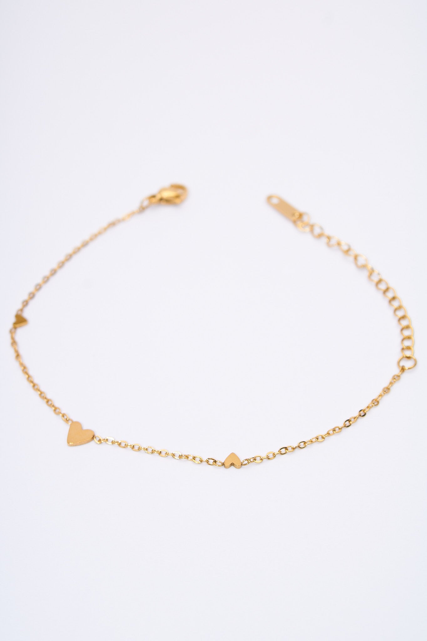 Pulsera fina con corazones espaciados — baño dorado