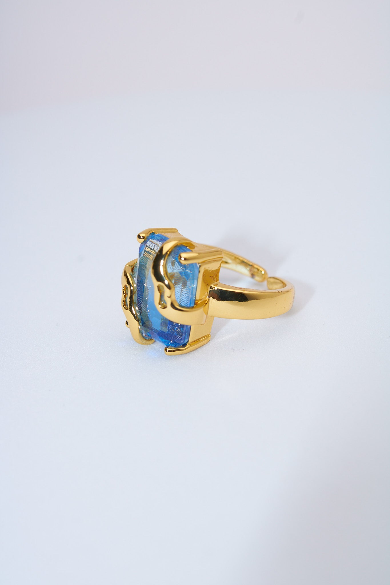 Anillo con piedra azul facetada — baño dorado