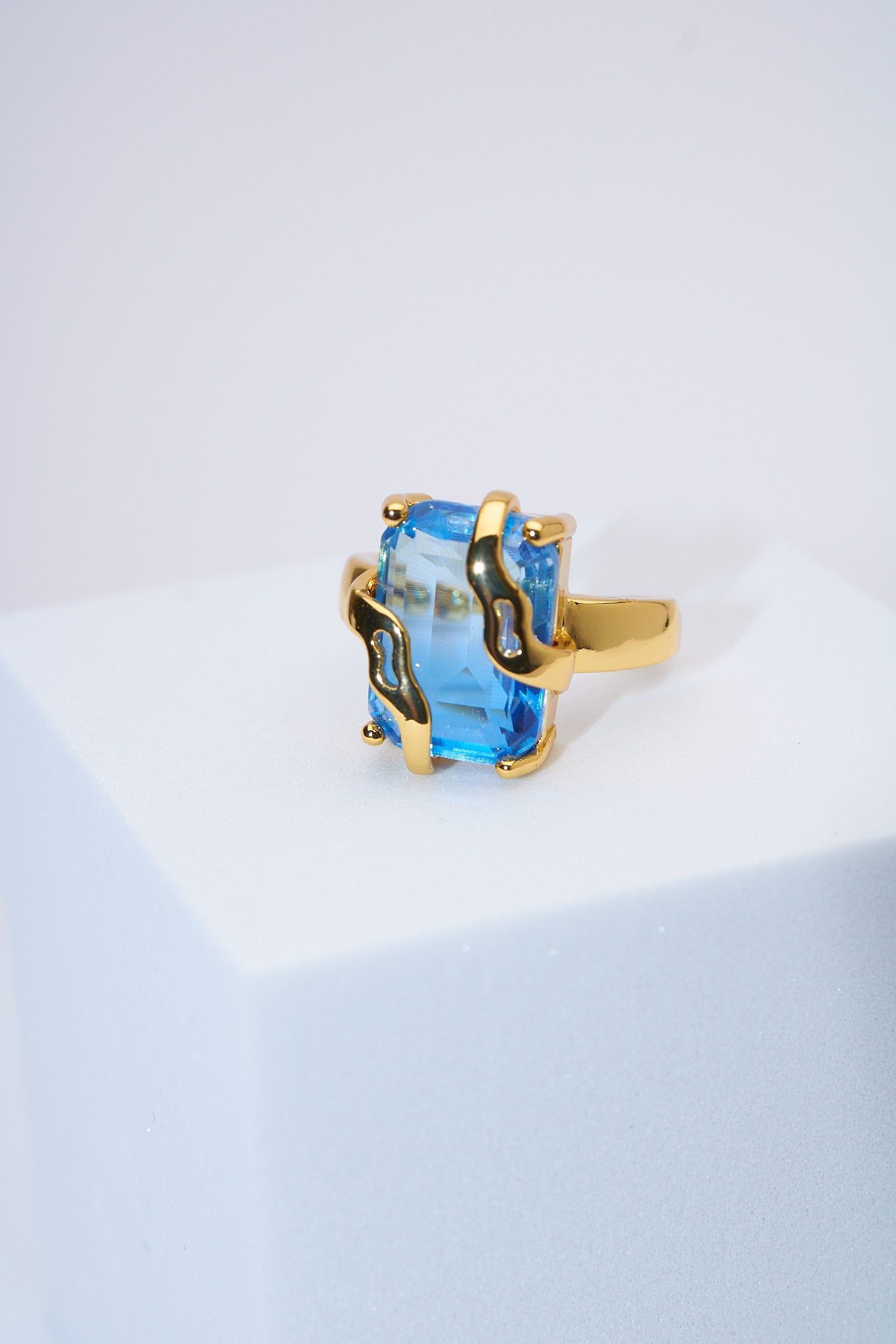 Anillo con piedra azul facetada — baño dorado