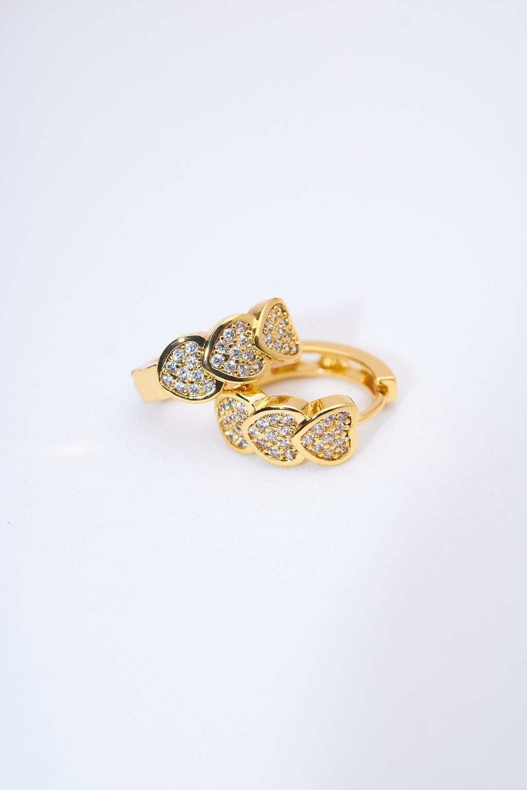 Aretes huggie corazones pavé dorados