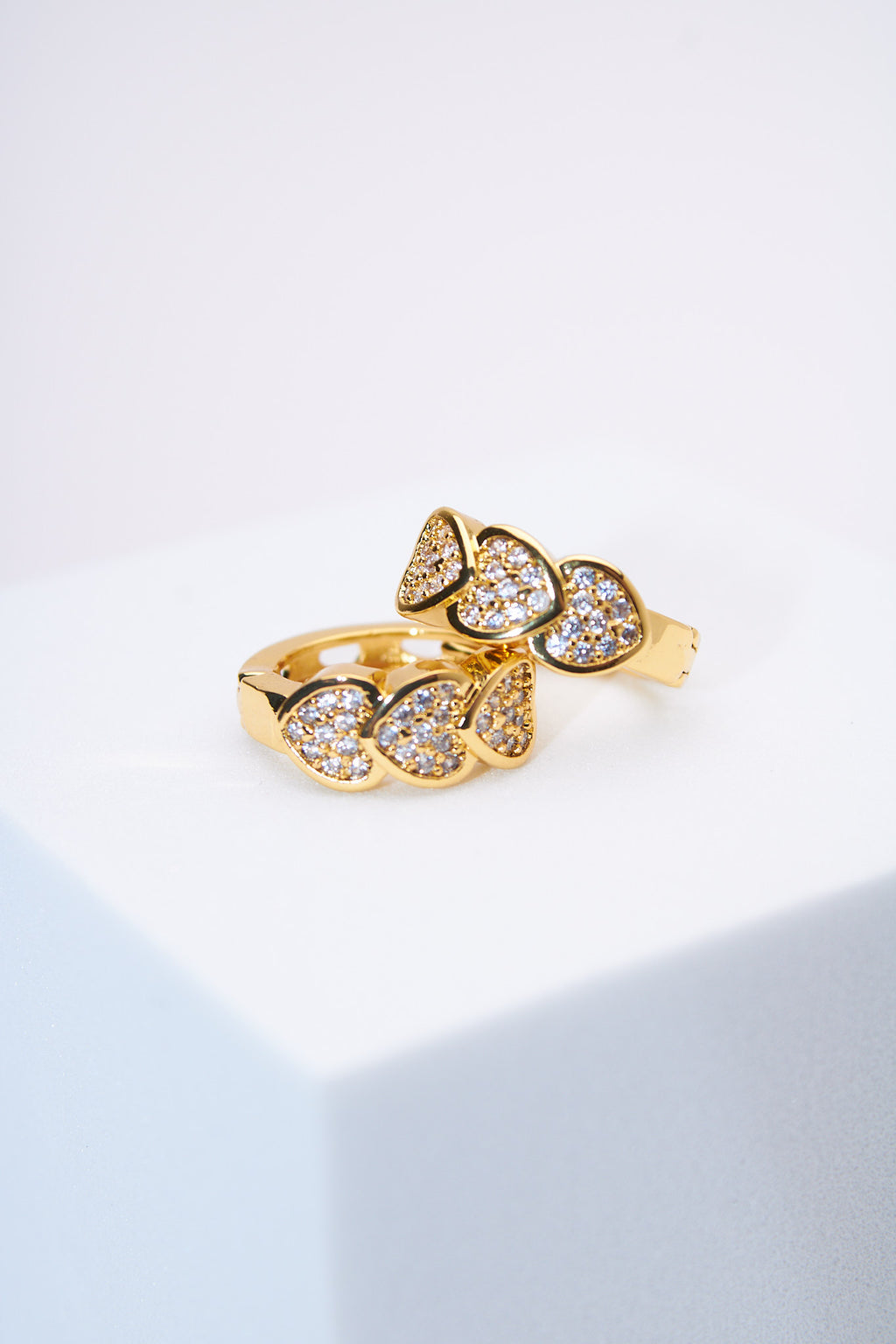 Aretes huggie corazones pavé dorados