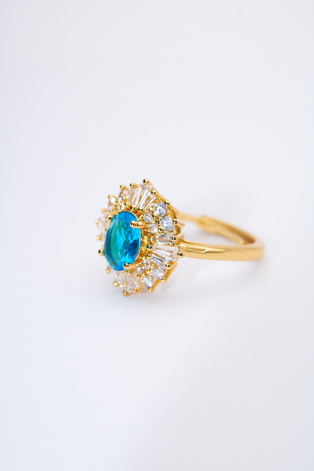 Anillo solitario floral con piedra azul y halo de cristales — baño dorado