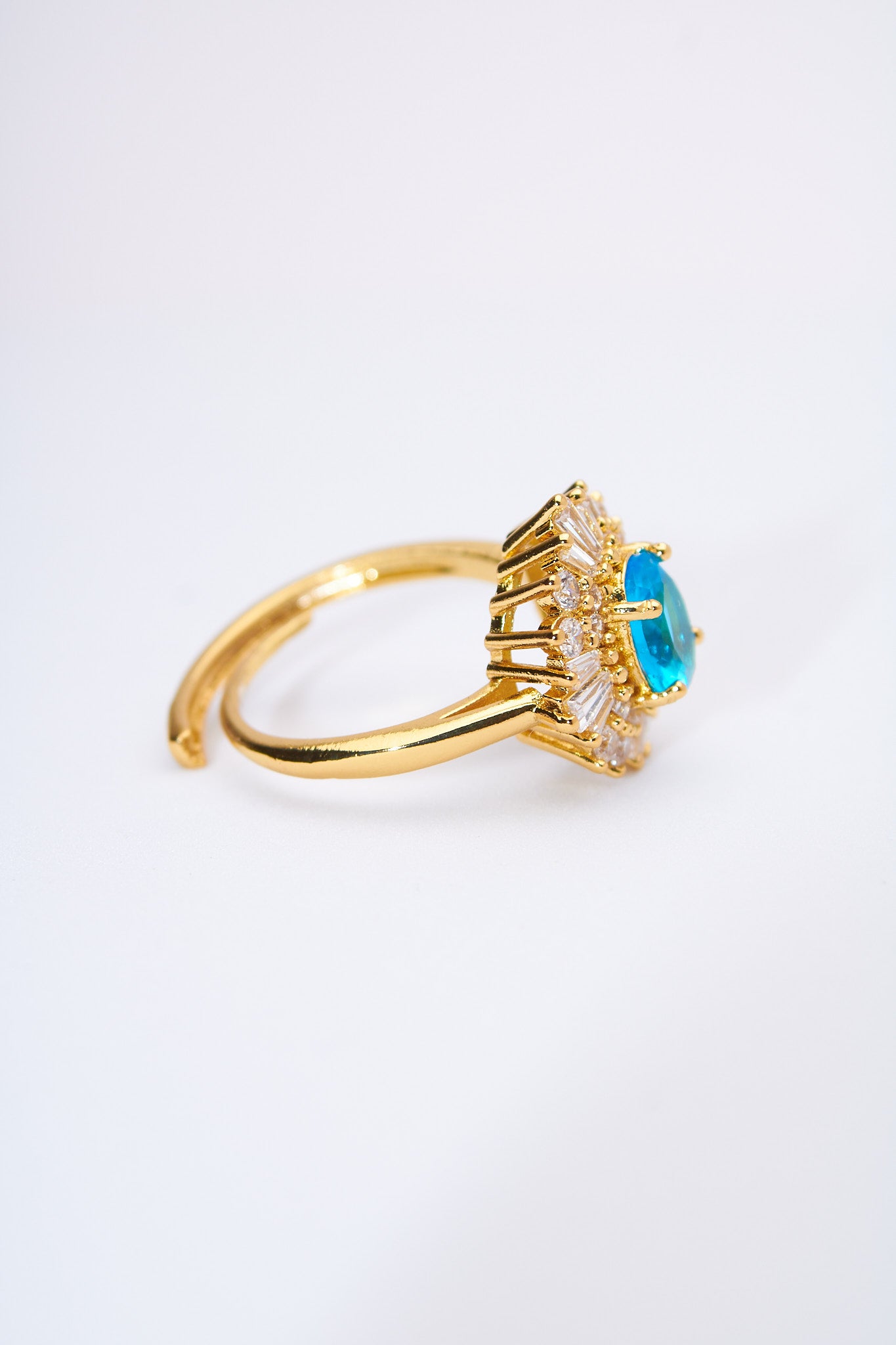 Anillo solitario floral con piedra azul y halo de cristales — baño dorado