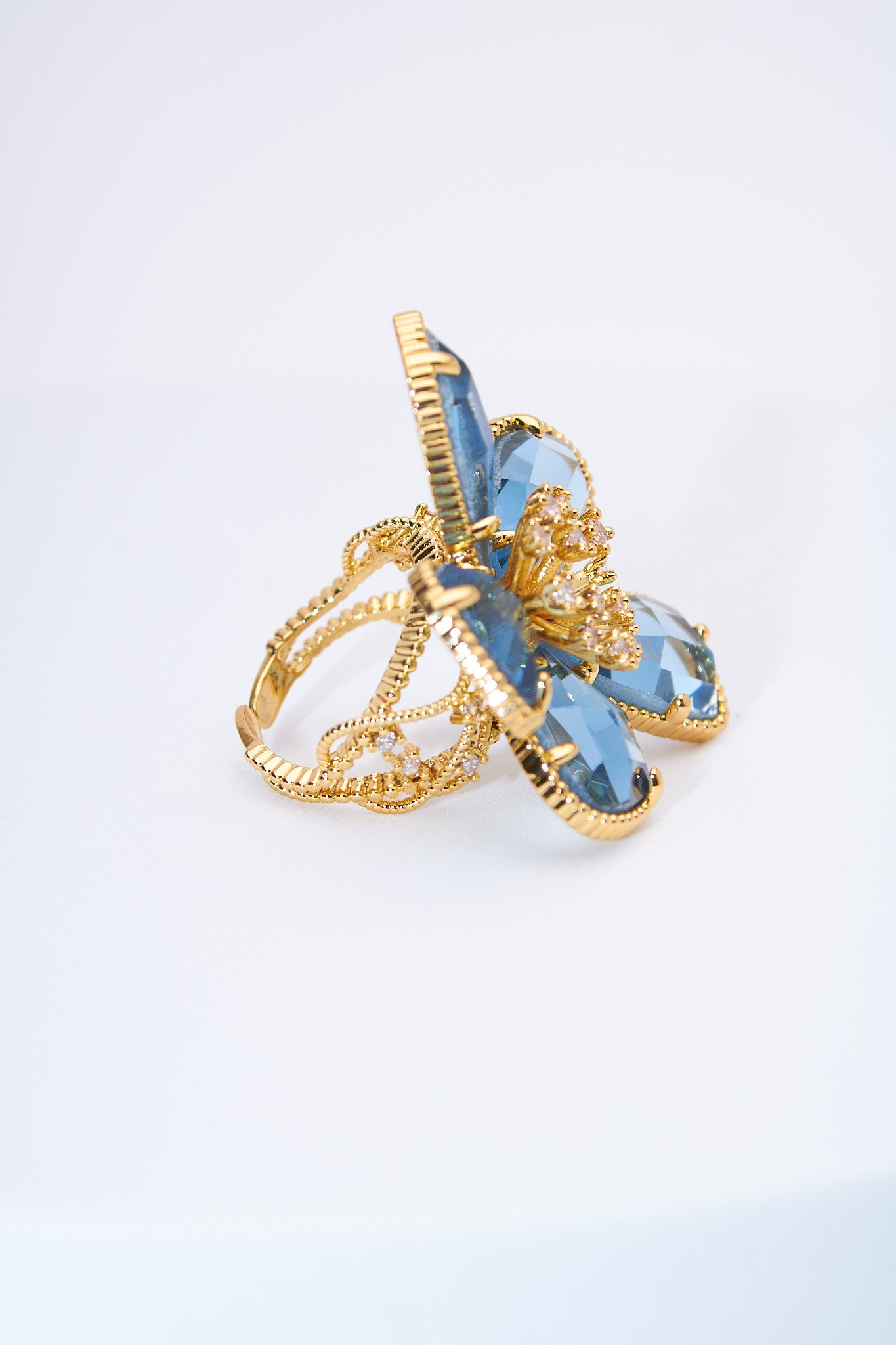 Anillo flor con pétalos lágrima azul claro — baño dorado